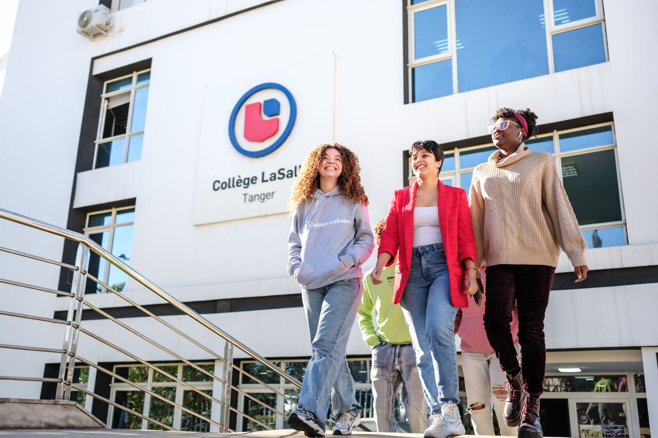 Trois étudiants heureux se promènent ensemble à l'extérieur du bâtiment du Collège LaSalle à Tanger.