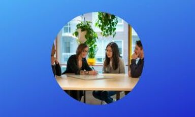 Quatre individus participant activement à une réunion autour d'une table dans un bureau moderne.