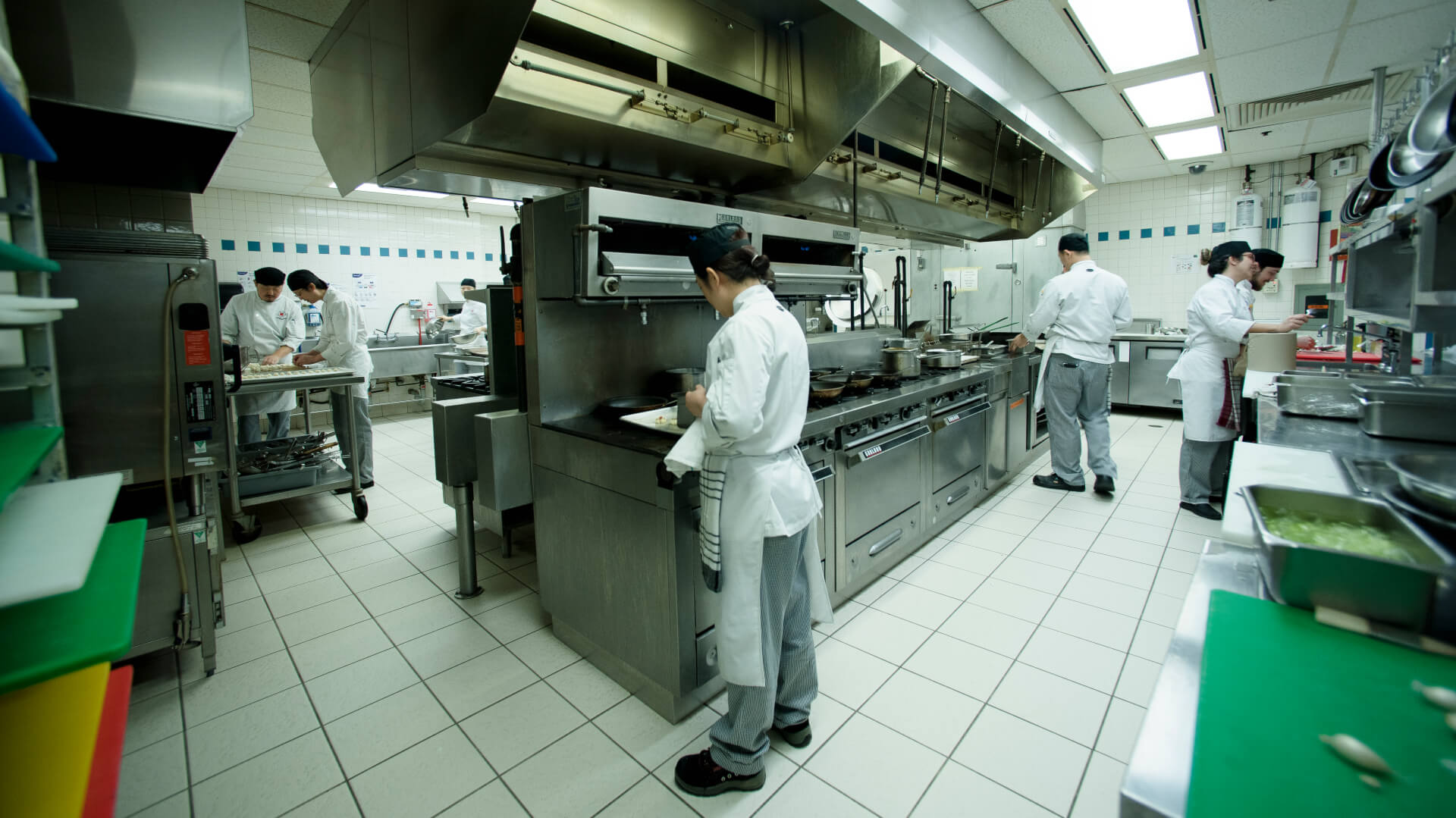 Students training in culinary arts work in unison in the well-equipped kitchen of a culinary school.