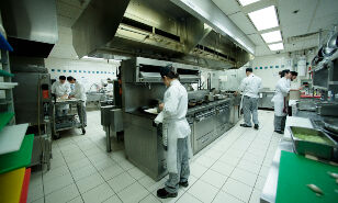 Students training in culinary arts work in unison in the well-equipped kitchen of a culinary school.
