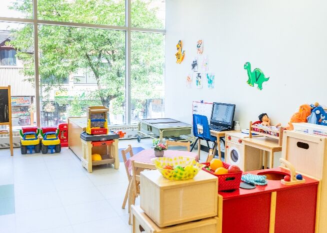 A well-lit preschool classroom with various learning stations and toys, ready for a day of activities.