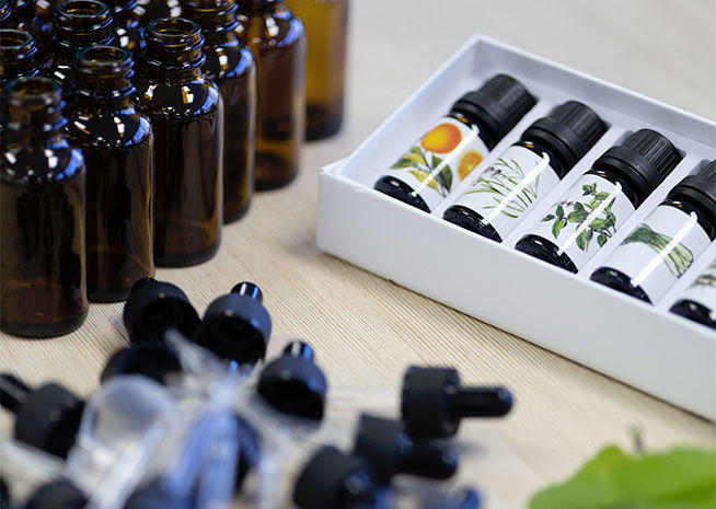 An assortment of amber bottles containing essential oils, displayed alongside their packaging on a wooden surface.