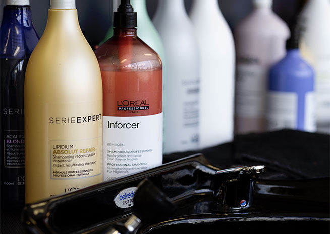 A close-up of professional L'Oréal haircare products and hairstyling tools on a salon workstation.