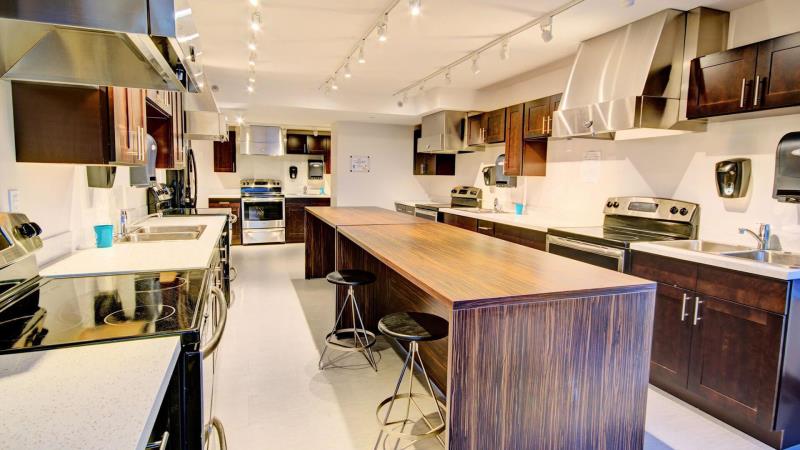 Spacious modern kitchen with stainless steel appliances, dark wood cabinets, and a long central island with seating.
