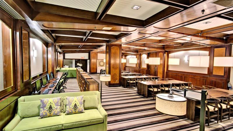 A classic hotel lounge with green sofas, striped carpet, and rich wooden paneling, exuding a sense of tradition and comfort.