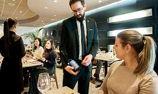 A sommelier presenting a bottle of wine to guests at a stylish restaurant with modern decor.