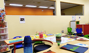 Zone d'art pour enfants accueillante avec fournitures de peinture et tables colorées, encourageant la créativité.