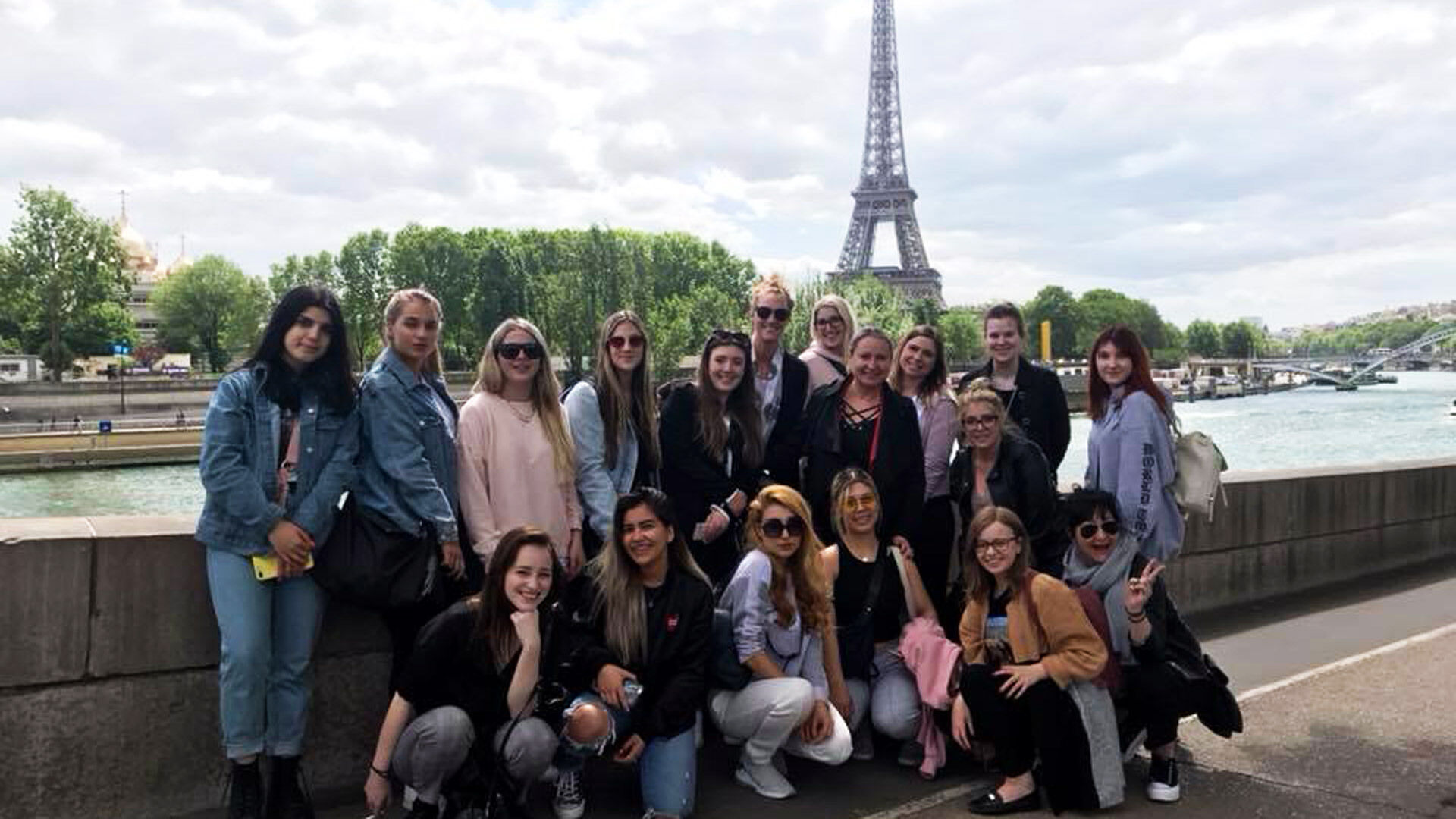  Un groupe de touristes avec la Tour Eiffel en arrière-plan, profitant d'une journée ensoleillée au bord de la Seine à Paris.