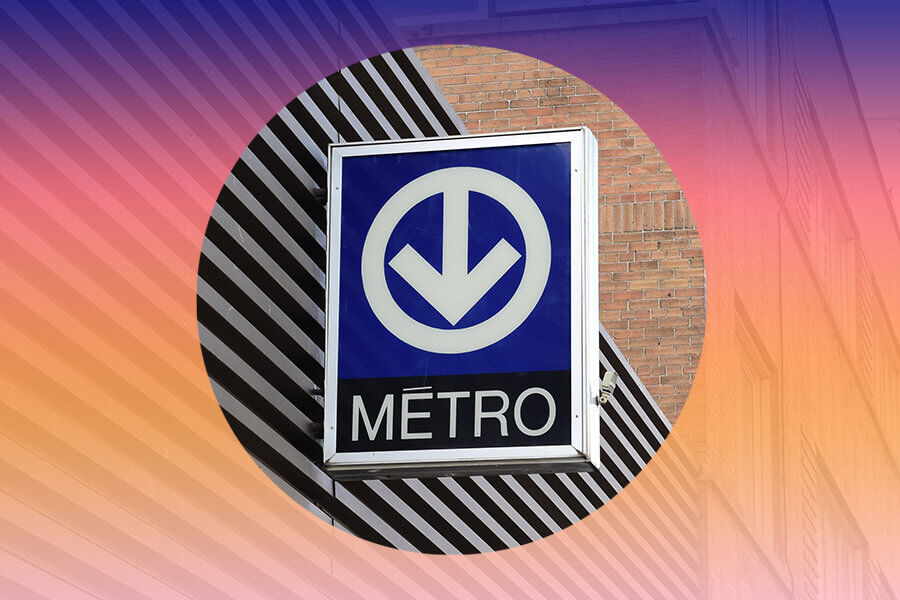A metro signboard with a downward arrow and the word "METRO" against a brick wall, with a striped pattern in the background.