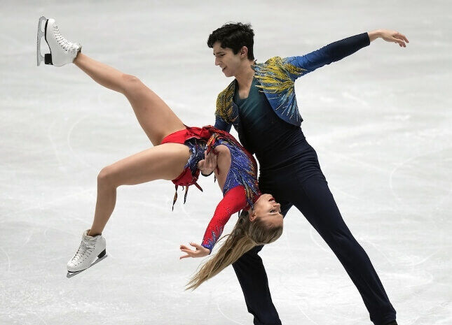 Couple de patinage artistique en pleine performance, réalisant un porté impressionnant avec élégance.