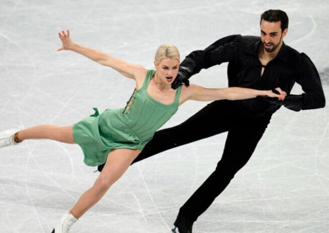 Duo de danse sur glace glissant sur la piste avec des poses dynamiques et synchronisées.