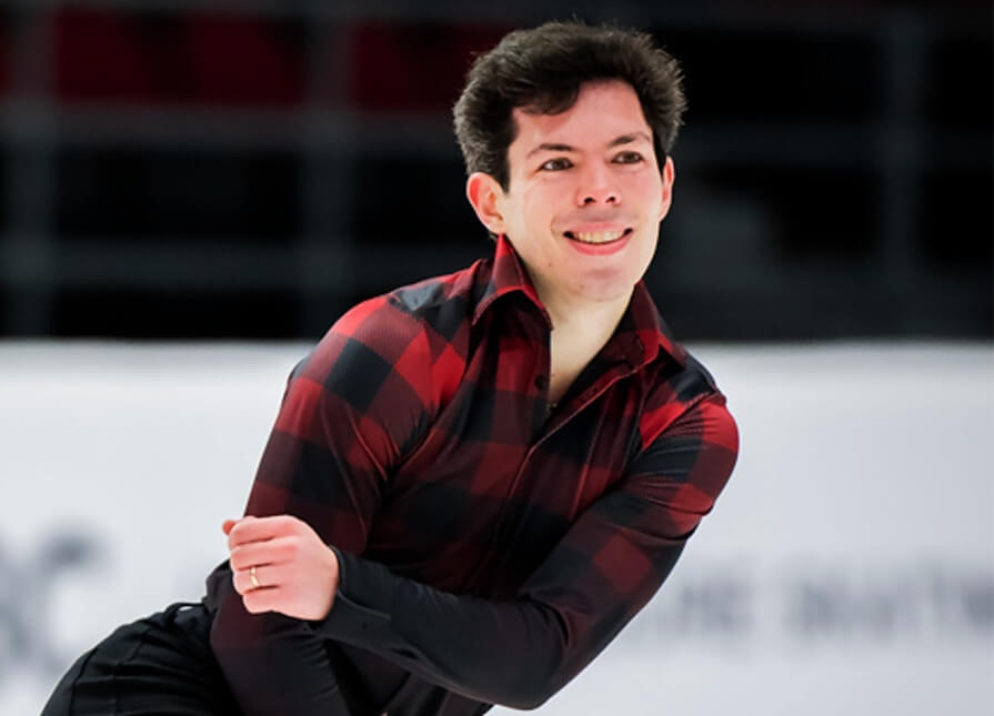 A figure skater in a red and black costume exhibits poise on ice.