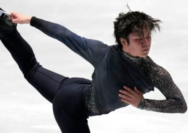 A figure skater in a dark, embellished outfit executes a precise move on the ice.