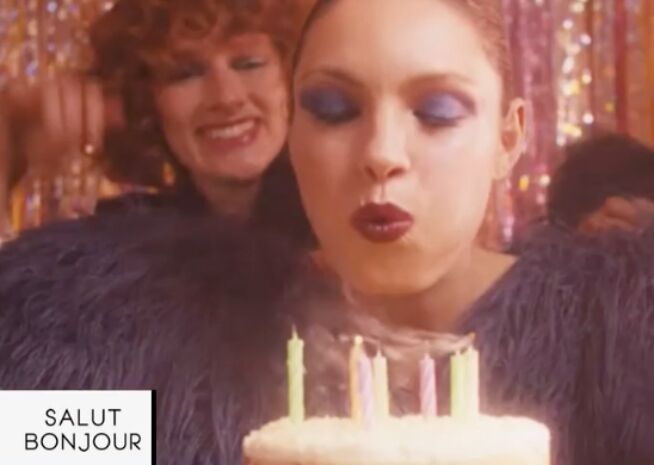 Une femme souffle les bougies sur un gâteau d'anniversaire, un moment de joie et de célébration capturé.