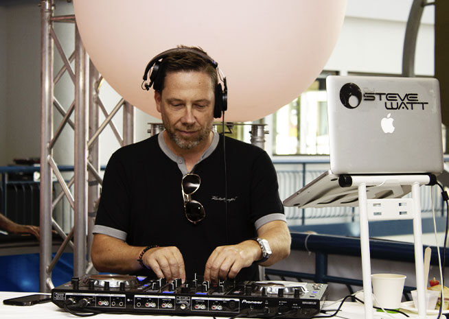 Un DJ se concentrant sur le mixage de morceaux à sa console pendant un événement.