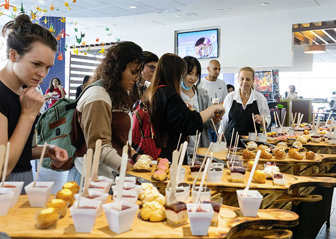 Guests sampling various dishes at a food tasting event, with a festive ambiance.