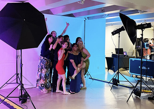 A group of smiling people posing together at a photo studio setup, capturing happy memories.