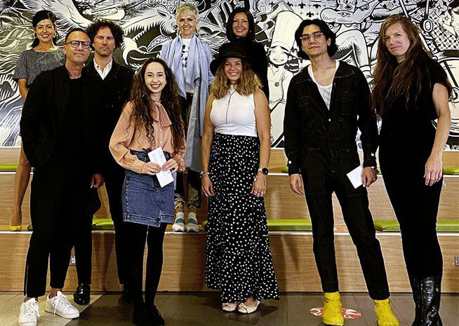 A diverse team of designers poses with confidence against an artistic backdrop, showcasing their collective talent.