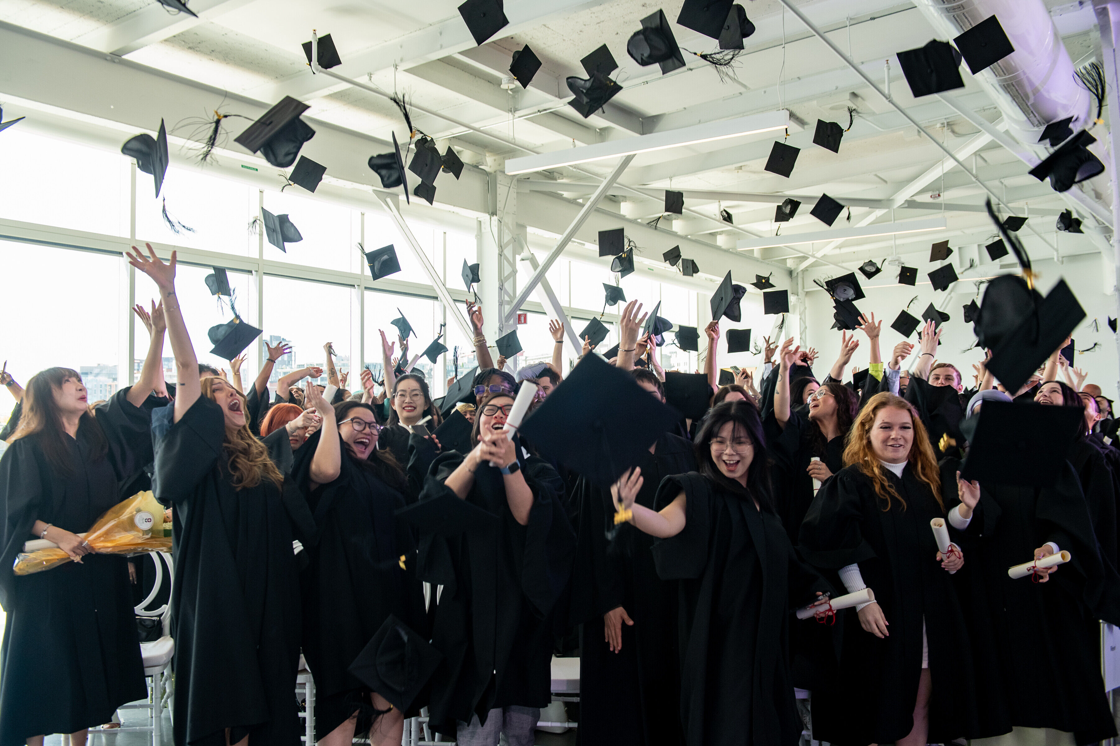 Un groupe de diplômés joyeux lance leurs chapeaux en l'air à l'intérieur.