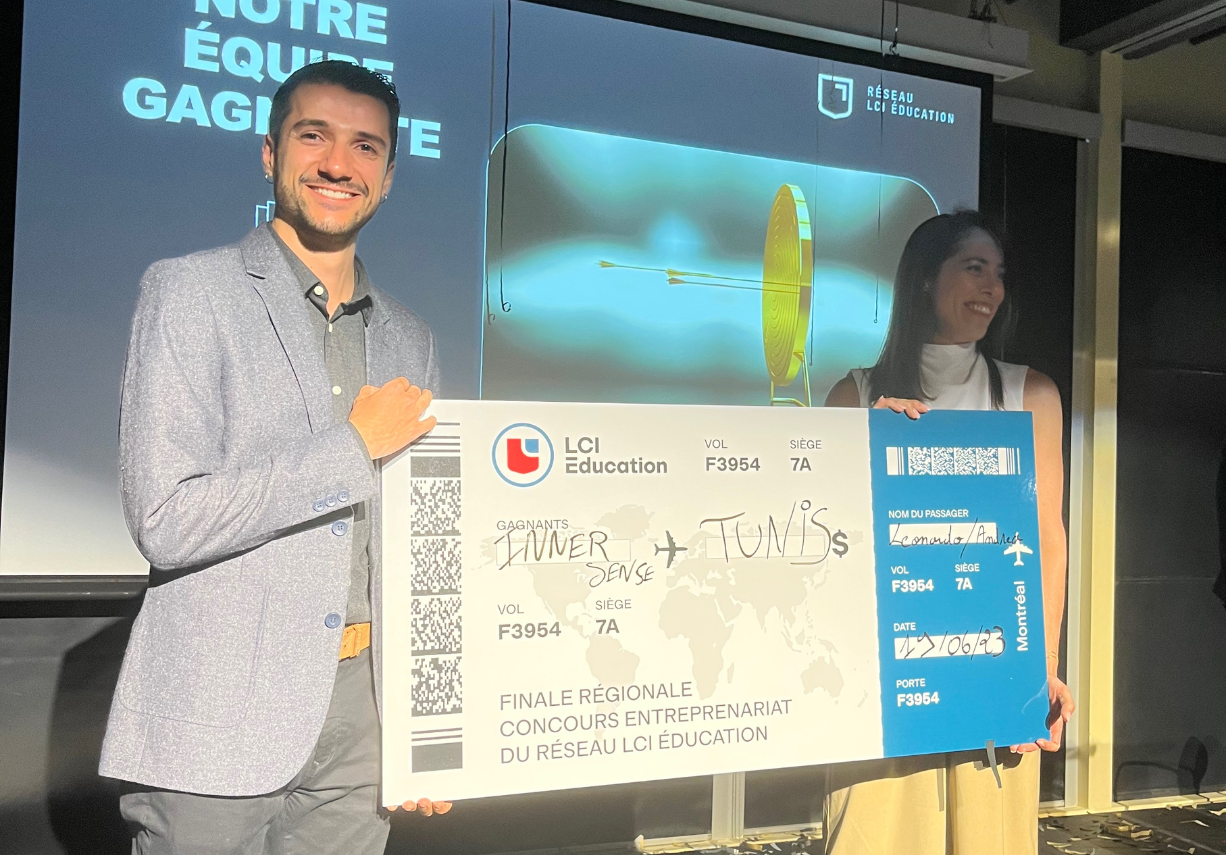 A man and a woman proudly display an oversized boarding pass after winning at an LCI Education network entrepreneurship competition.