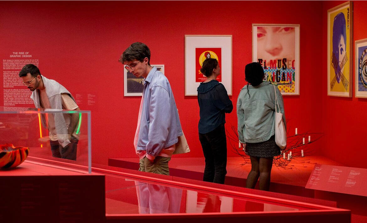Visitors observing artworks at a vibrant red-themed graphic design exhibition.