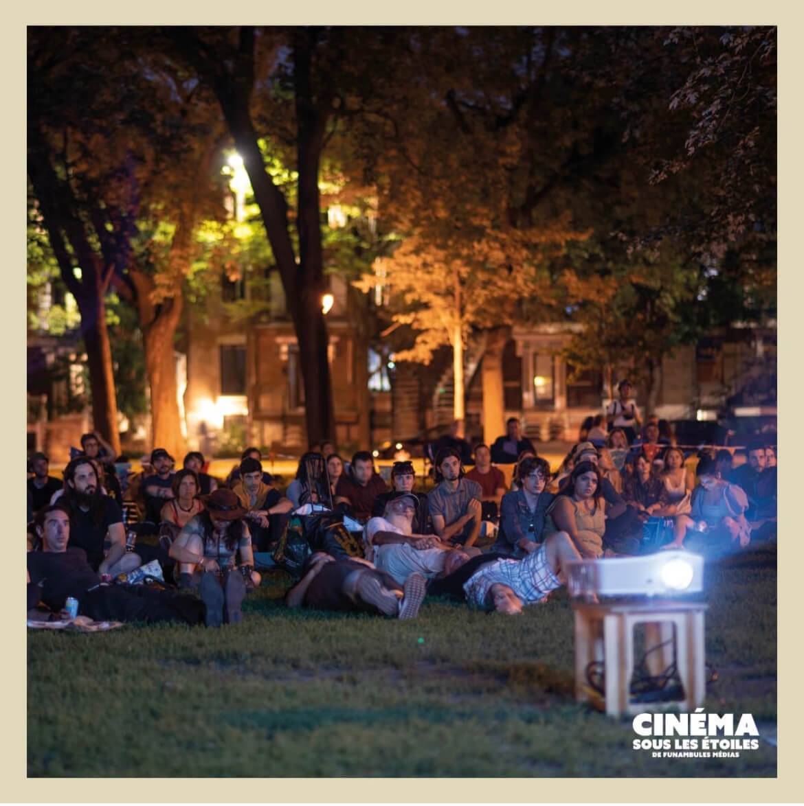 Un public attentif apprécie un film dans un parc au crépuscule, illustrant la communauté et les loisirs.