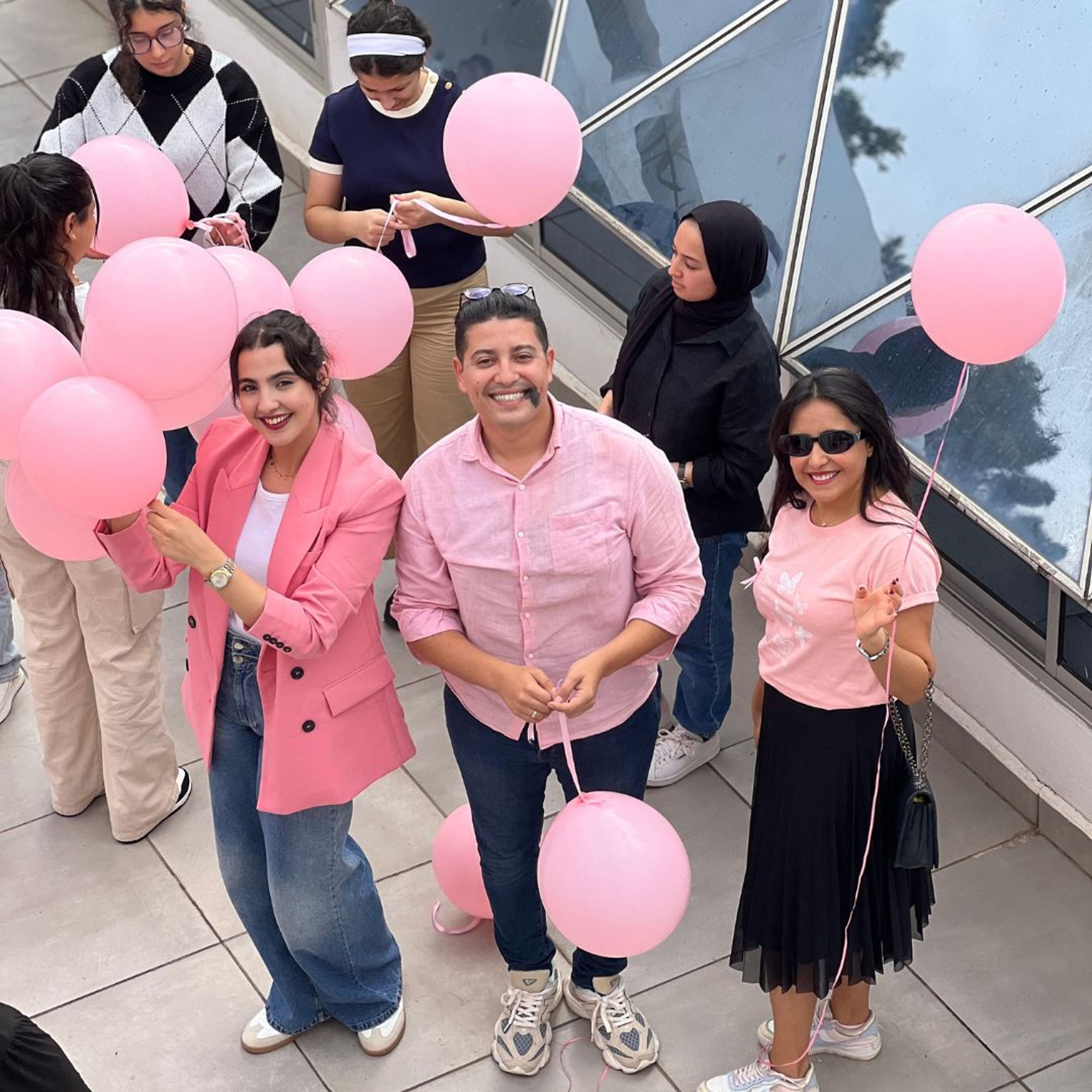 Participants célébrant la sensibilisation au cancer du sein avec des ballons roses