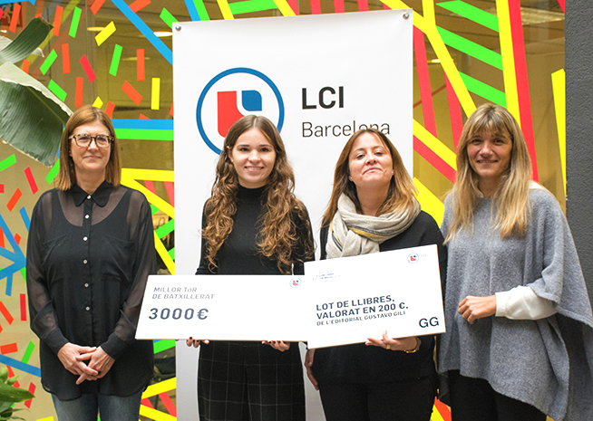 Cuatro mujeres sonríen en una ceremonia de entrega de premios, con la receptora sosteniendo un cheque de beca frente a un banner de LCI Barcelona.