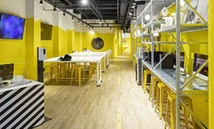 Un espai de treball dinàmic amb accents grocs brillants, mobiliari modern i una disposició oberta per a la col·laboració.
