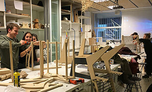 Estudiants de disseny participen activament en un taller, construint models amb diverses eines i materials.