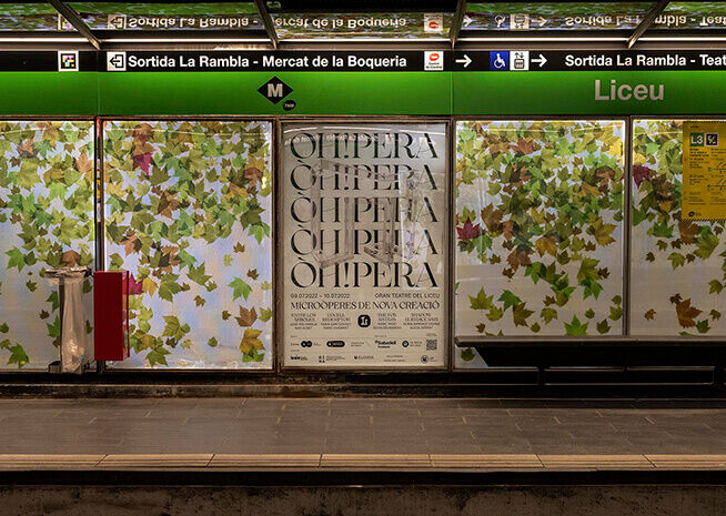 A subway station platform with vibrant leaf-patterned advertisements for an opera event at Liceu Theater.