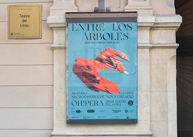 A poster on a wall advertising "Entre los Árboles," a performance by José Río-Pareja and Nao Albet, scheduled from July 9 to 10, 2022, at Gran Teatre del Liceu.