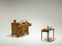An antique carpenter's workbench equipped with various traditional tools, next to a smaller table with a vise and hand tools.