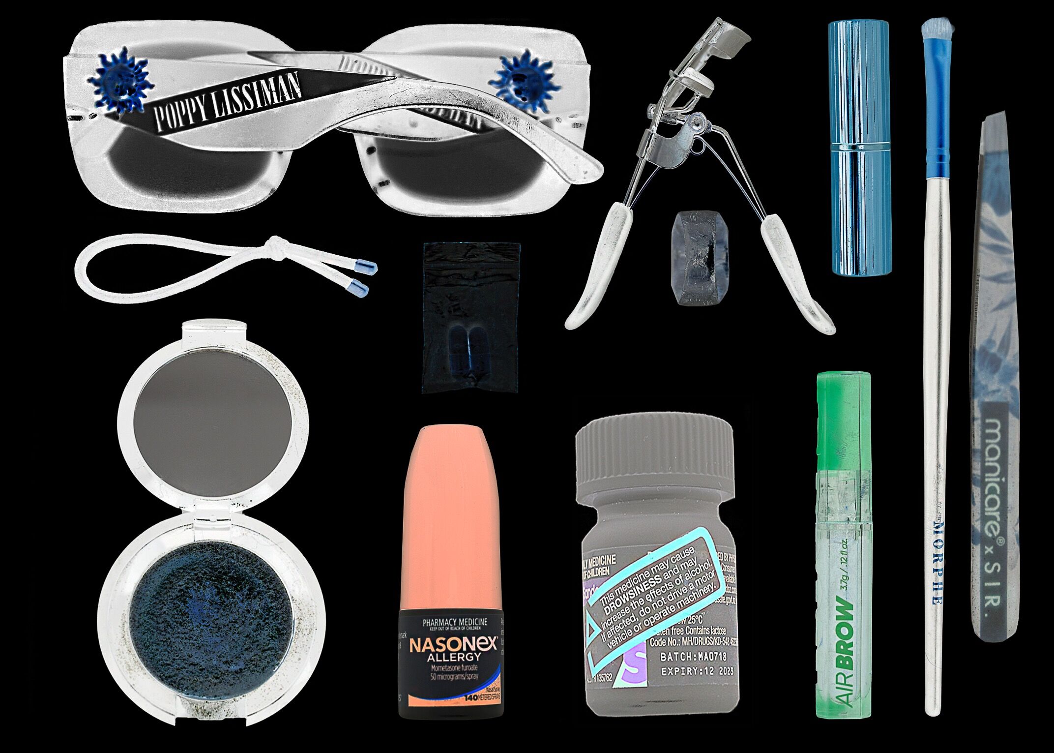 A collection of personal care items including decorated sunglasses, a compact mirror, and cosmetic tools, alongside medical items like a nasal spray and prescription bottles.